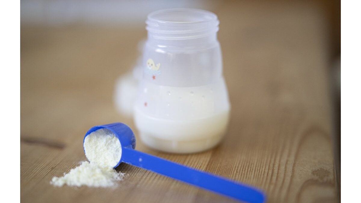 Bambino beve latte da un bicchiere in cucina.