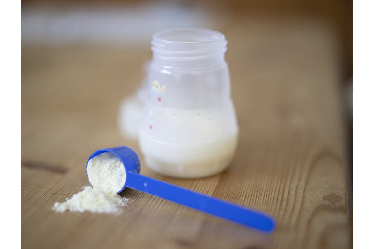 Bambino beve latte da un bicchiere in cucina.