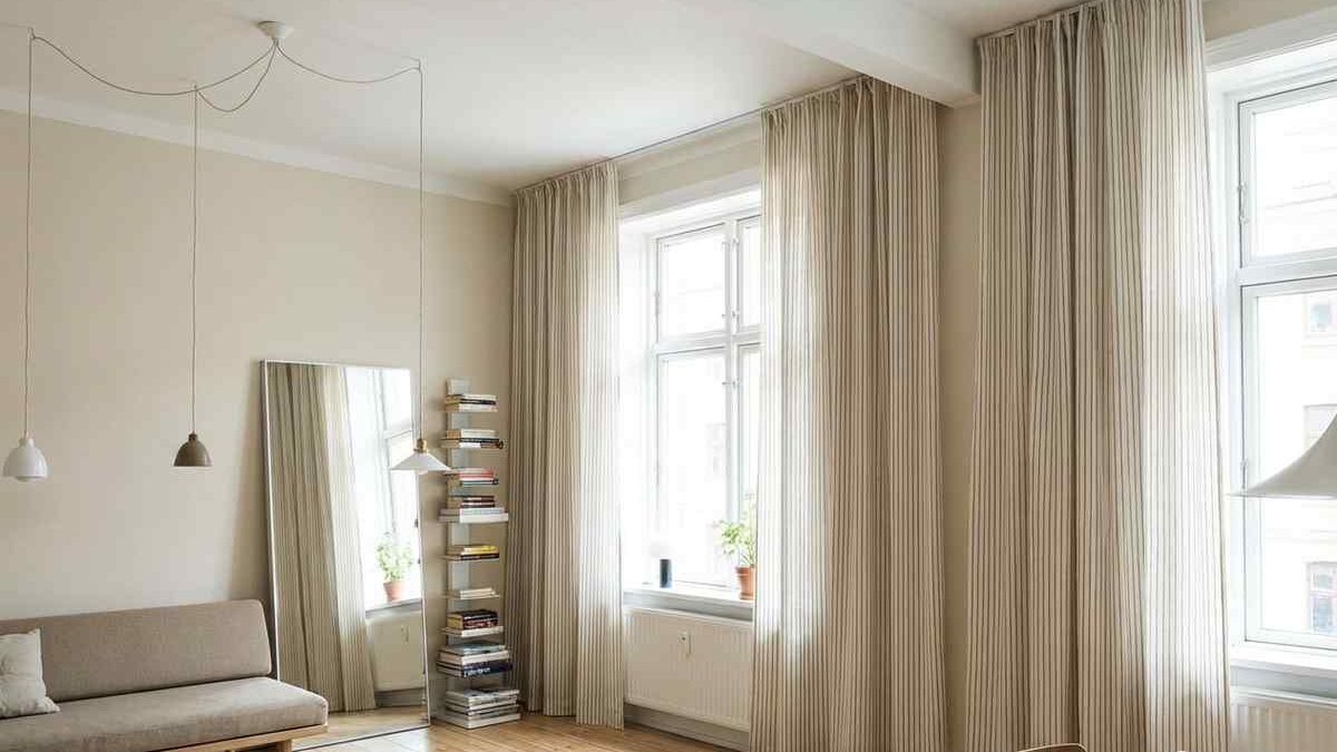 Stanza con pareti chiare e tende lunghe fino al pavimento.