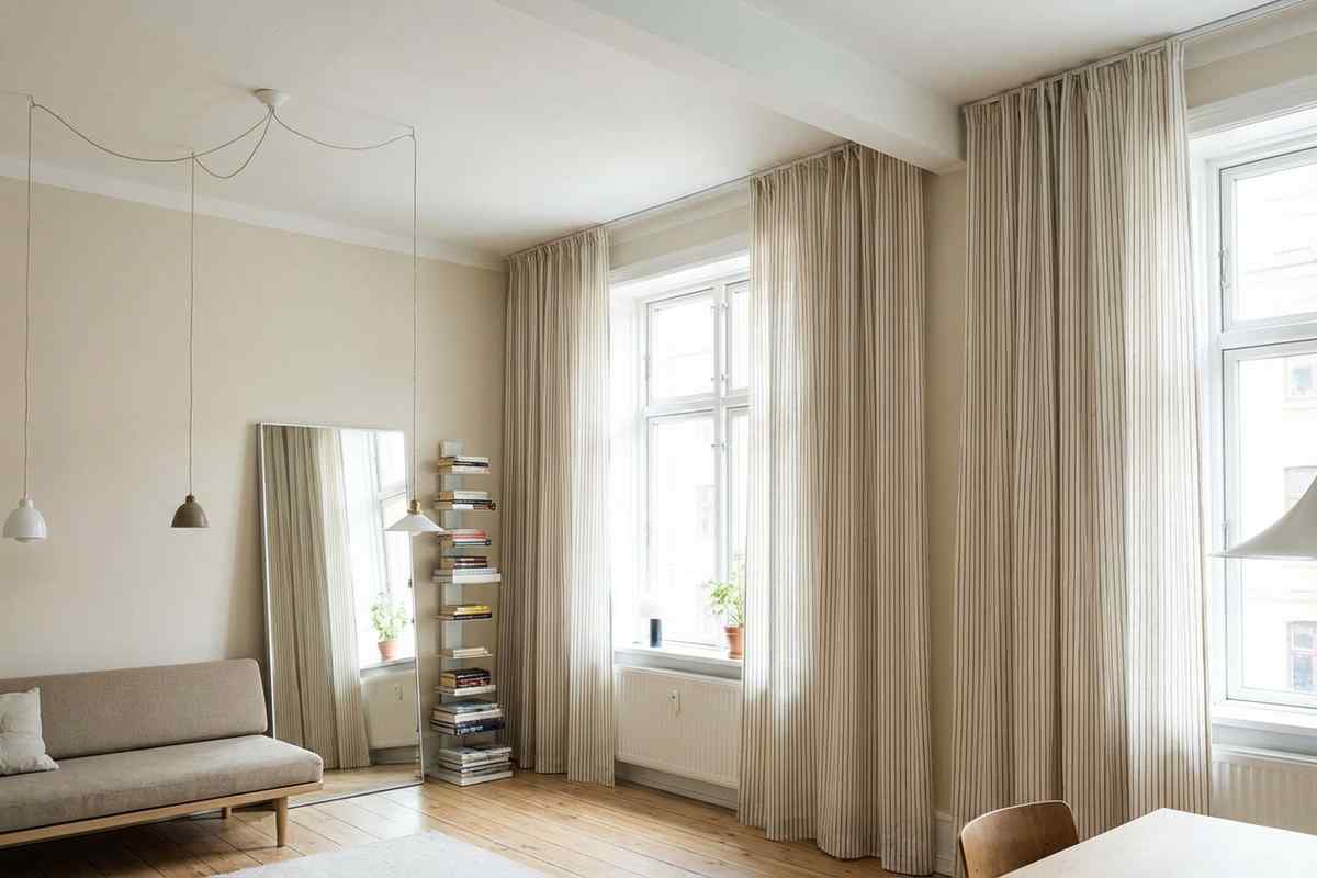Stanza con pareti chiare e tende lunghe fino al pavimento.