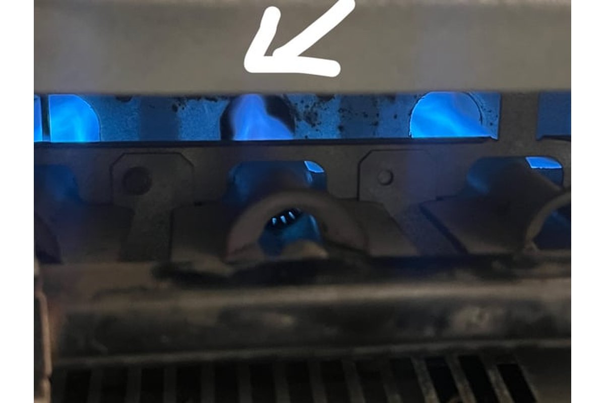 Bruciatore a gas con fiamma debole su fornello da cucina.