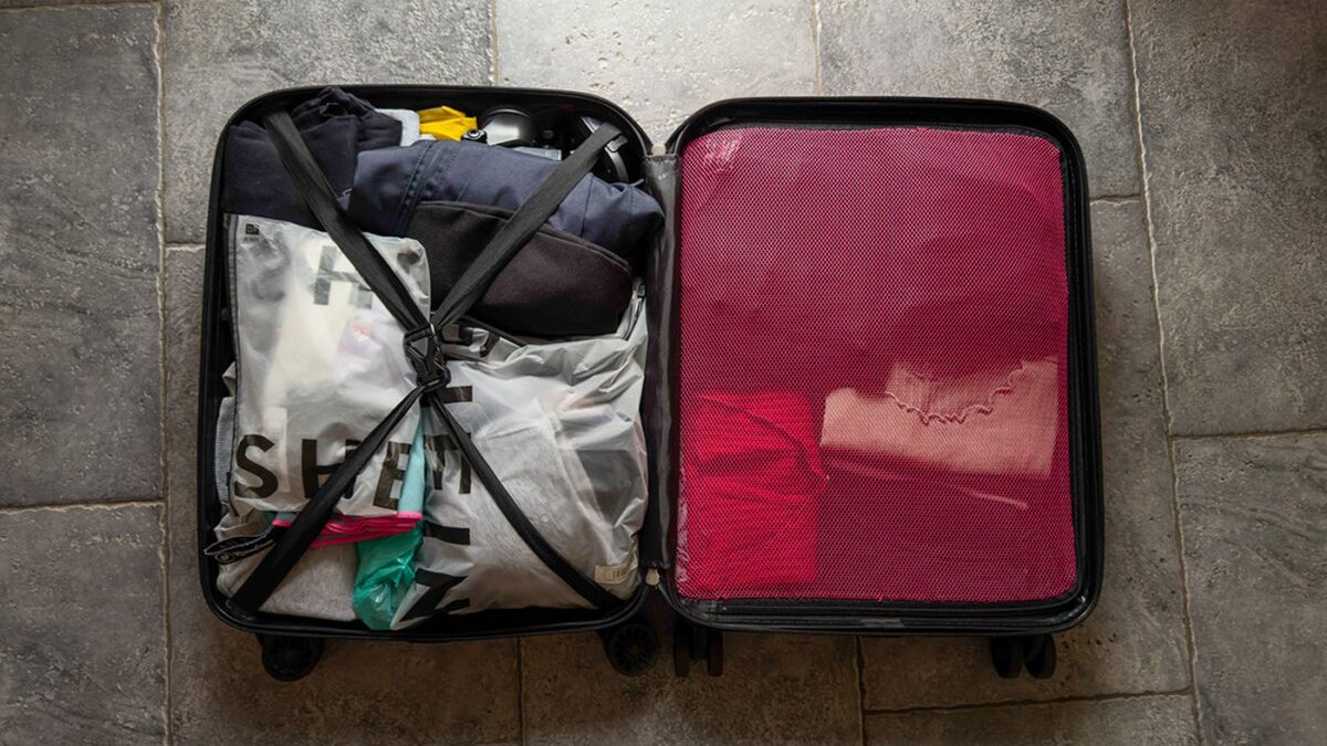 Valigia aperta con vestiti piegati e accessori da viaggio.