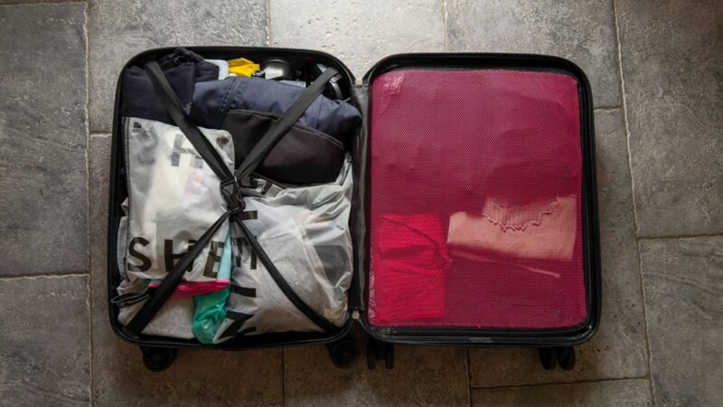 Valigia aperta con vestiti piegati e accessori da viaggio.