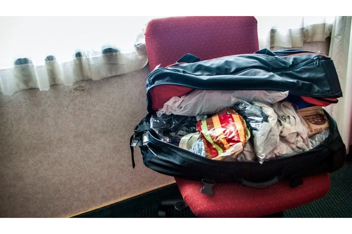 Valigia aperta con vestiti piegati e accessori da viaggio.