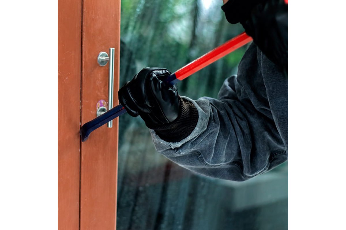 Ladro tenta di aprire una porta con attrezzi da scasso.