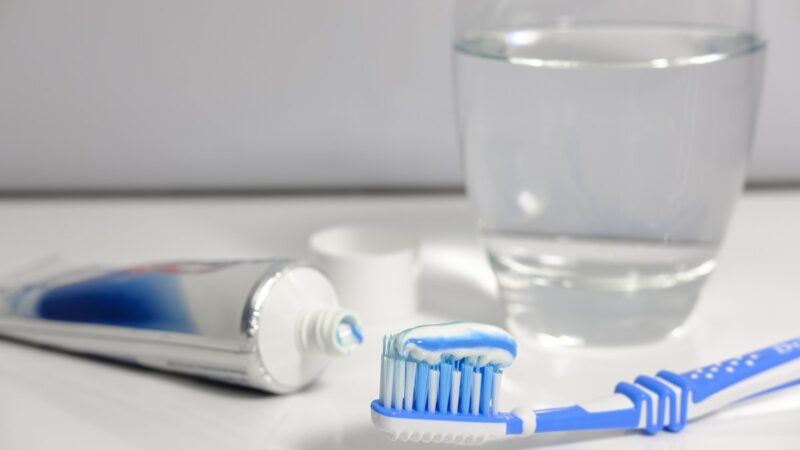 Dentifricio applicato su un rubinetto in bagno per la pulizia.