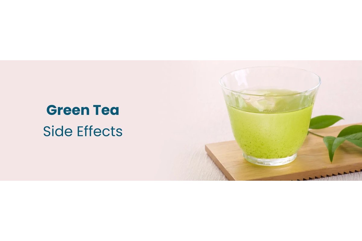 Tazza di tè verde fumante su un tavolo di legno con foglie di tè accanto.