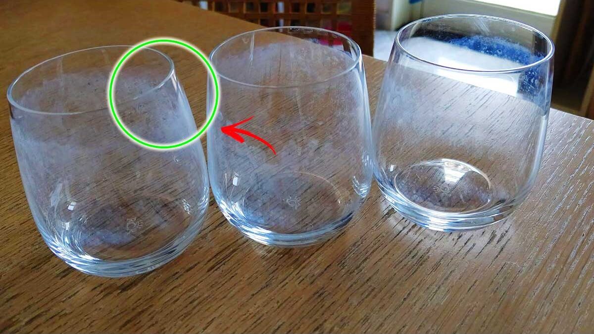 Bicchieri e stoviglie con macchie bianche su un tavolo di legno.