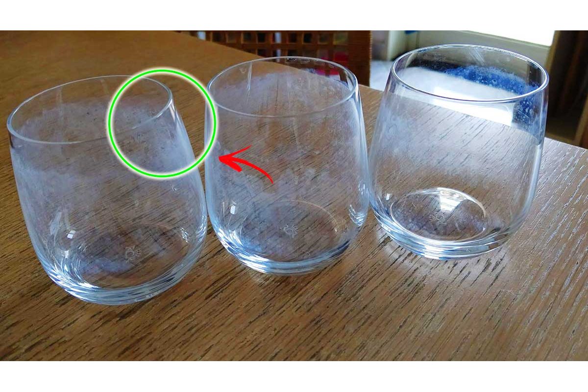 Bicchieri e stoviglie con macchie bianche su un tavolo di legno.