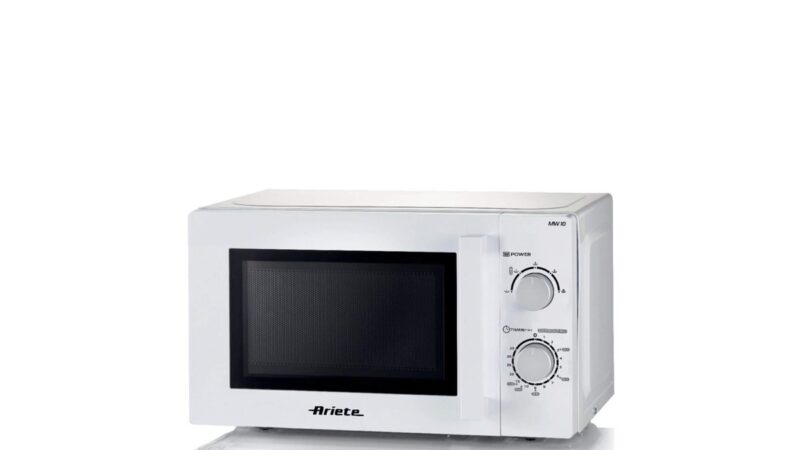 Persona che riscalda cibo nel microonde con un piatto coperto.