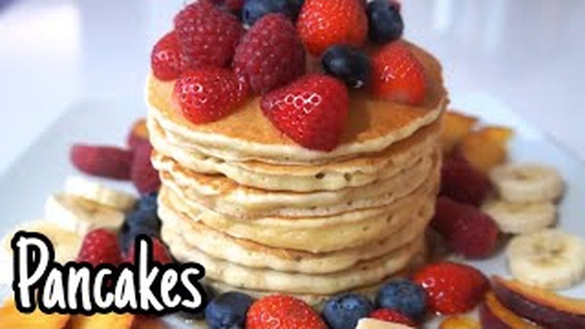 Pancake dorati impilati con ripieno cremoso e guarnizioni colorate