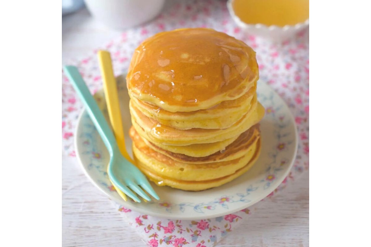 Pancake dorati impilati con ripieno colorato di frutta e crema.