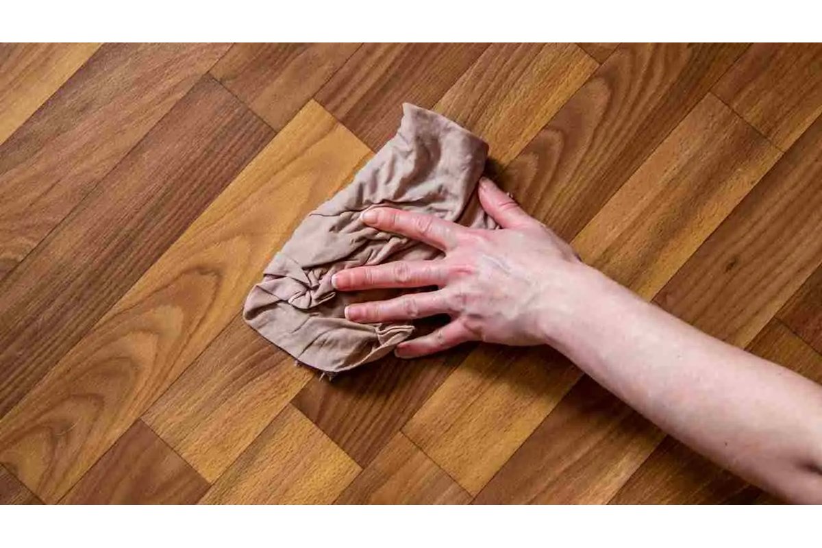 Bottiglia di aceto bianco accanto a pavimento in parquet lucido.