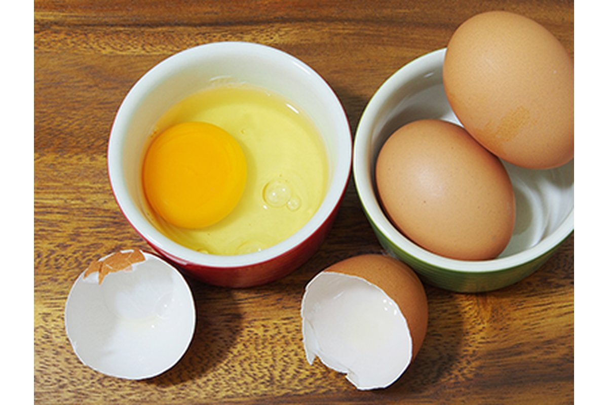 Uova fresche non lavate in un cartone su un tavolo di legno.
