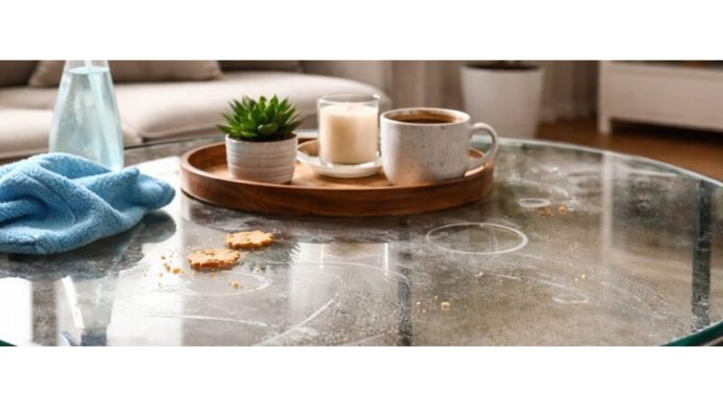 Tavolo di vetro con aloni e impronte visibili alla luce del sole.