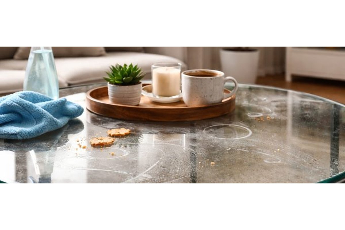 Tavolo di vetro con aloni e impronte visibili alla luce del sole.