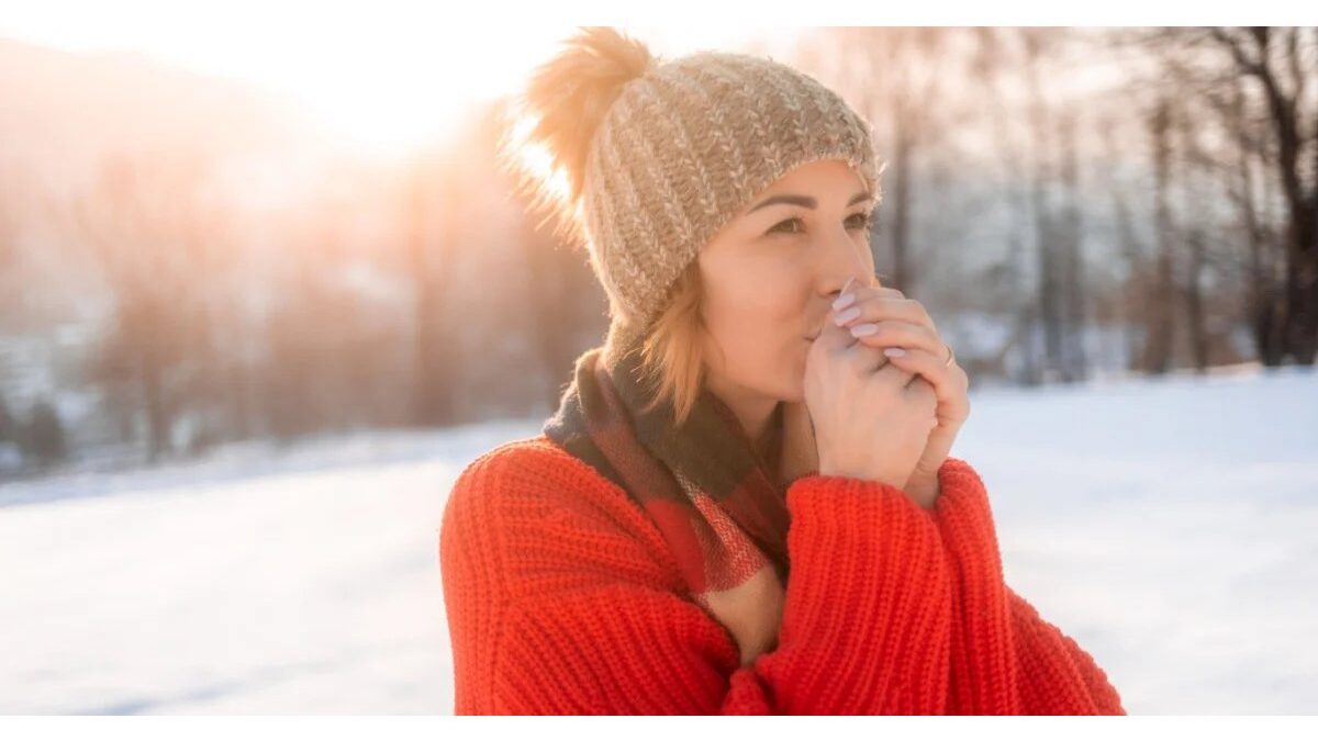 Persona che massaggia il ginocchio dolorante in un ambiente invernale