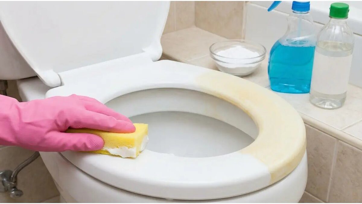 WC ingiallito con prodotti per la pulizia accanto.